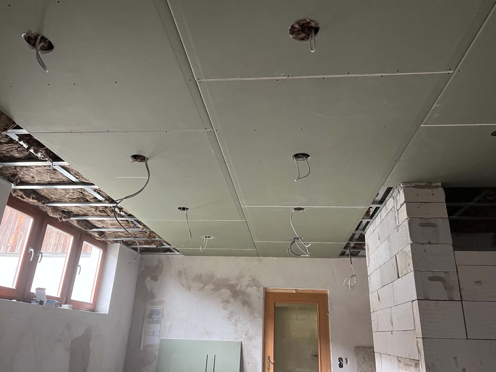 Boarded drywall ceiling with cut-out downlight holes and wired connections