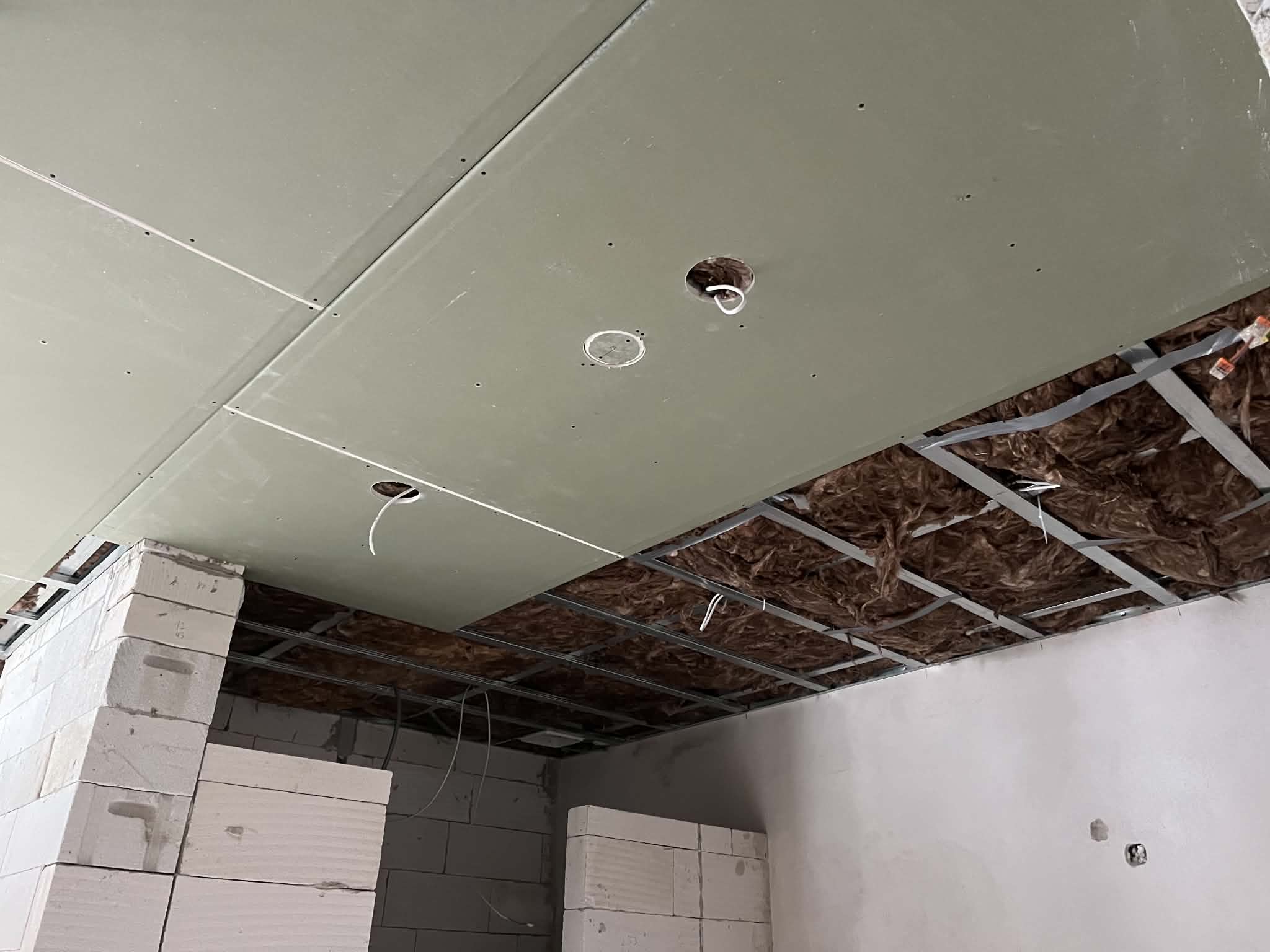 Partly boarded drywall ceiling with exposed insulation and metal framing